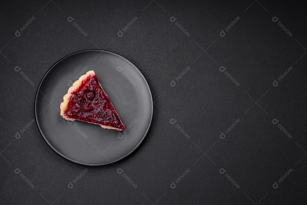 Deliciosa torta doce perfumada com bagas de cereja em uma placa de cerâmica sobre um fundo escuro de concreto