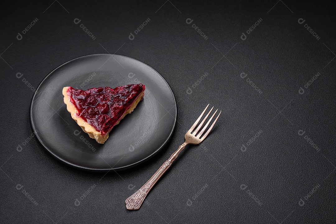 Deliciosa torta doce perfumada com bagas de cereja em uma placa de cerâmica sobre um fundo escuro de concreto
