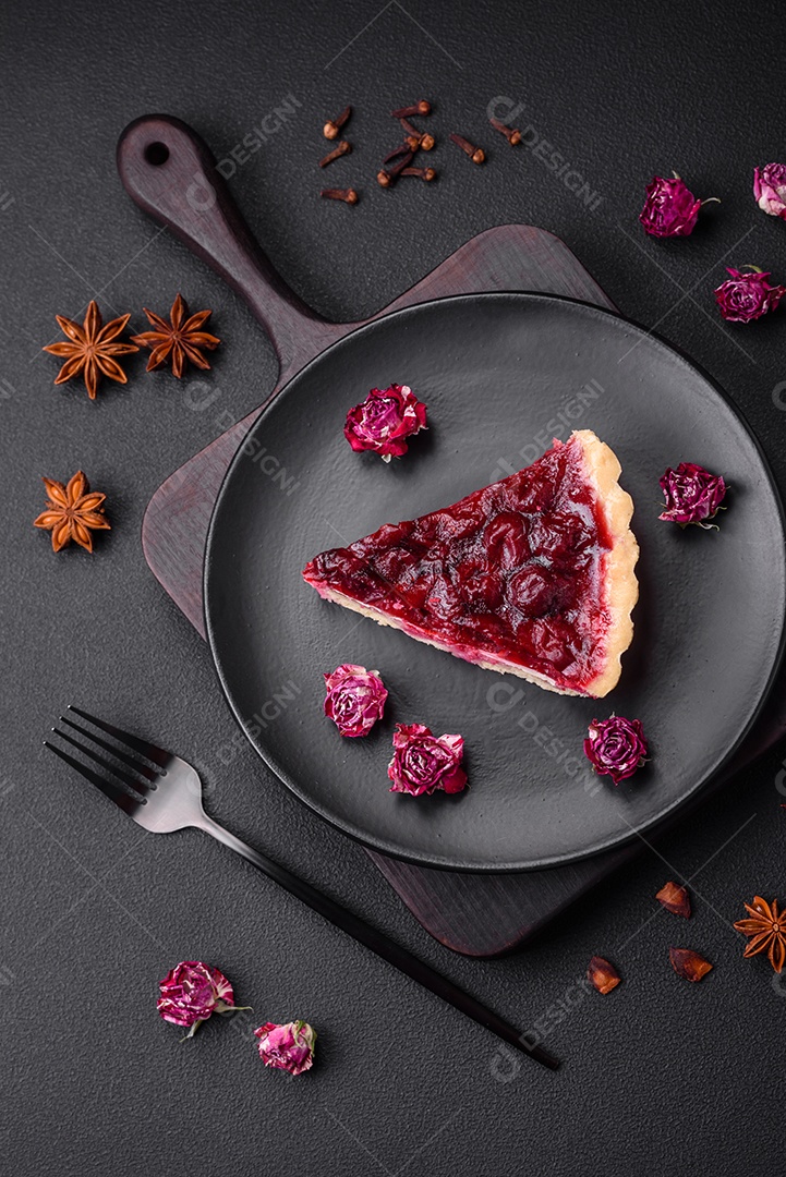 Deliciosa torta doce perfumada com bagas de cereja em uma placa de cerâmica sobre um fundo escuro de concreto