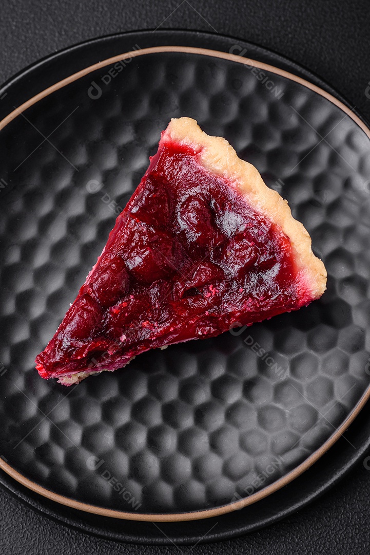 Deliciosa torta doce perfumada com bagas de cereja em uma placa de cerâmica sobre um fundo escuro de concreto