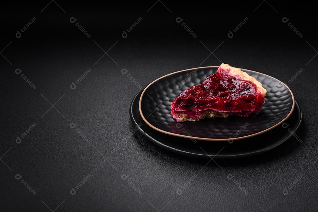 Deliciosa torta doce perfumada com bagas de cereja em uma placa de cerâmica sobre um fundo escuro de concreto