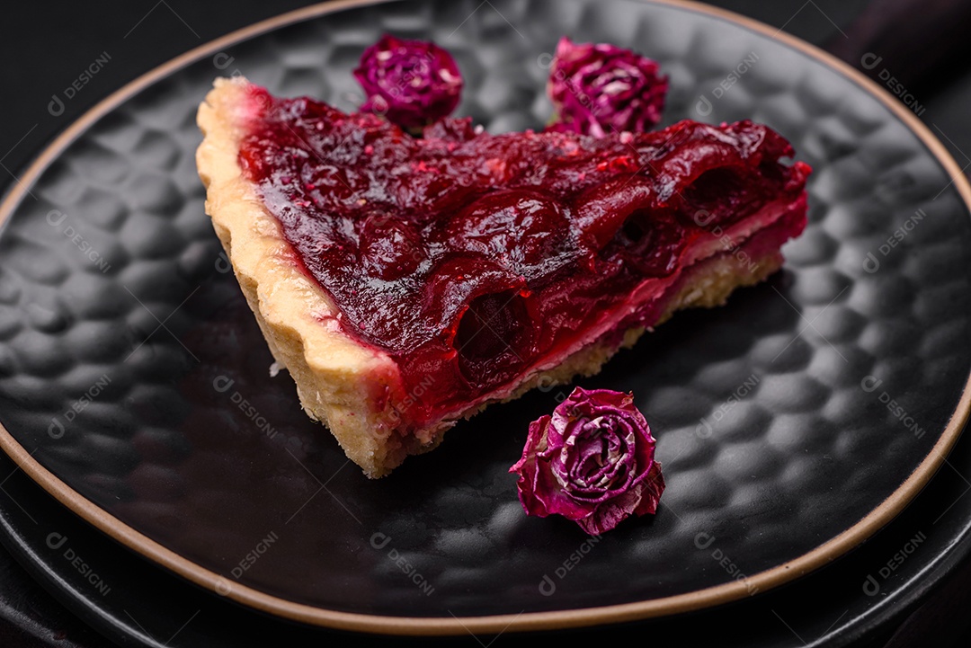 Deliciosa torta doce perfumada com bagas de cereja em uma placa de cerâmica sobre um fundo escuro de concreto