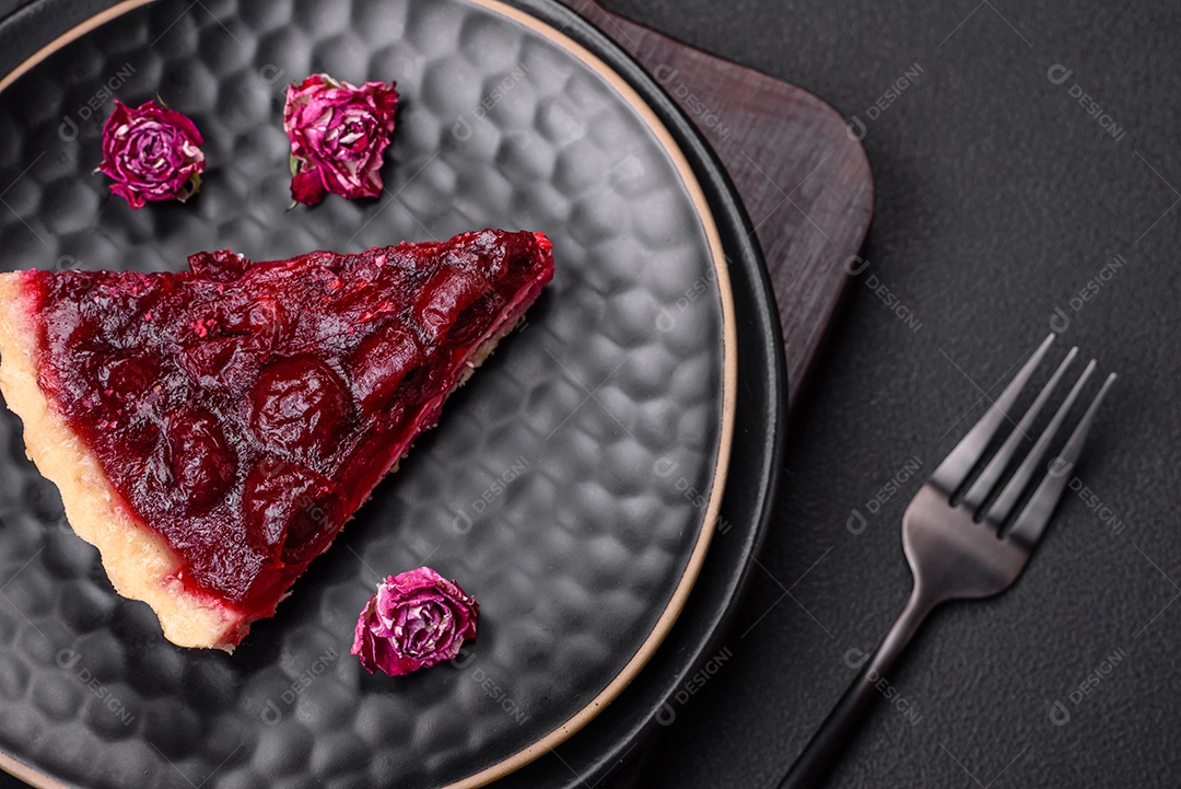 Deliciosa torta doce perfumada com bagas de cereja em uma placa de cerâmica sobre um fundo escuro de concreto
