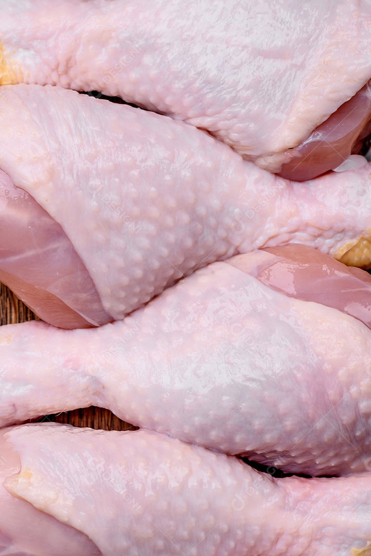 Pernas de frango cru com sal, especiarias e ervas sobre um fundo escuro de concreto