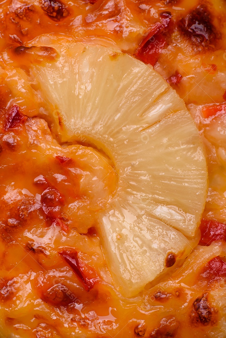 Filé de frango grelhado em forma de bife com tomate, abacaxi e queijo sobre fundo escuro de concreto