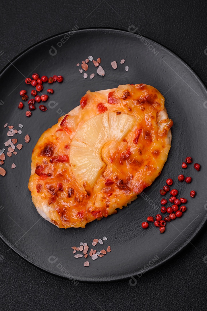 Filé de frango grelhado em forma de bife com tomate, abacaxi e queijo sobre fundo escuro de concreto