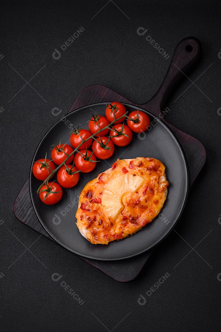 Filé de frango grelhado em forma de bife com tomate, abacaxi e queijo sobre fundo escuro de concreto