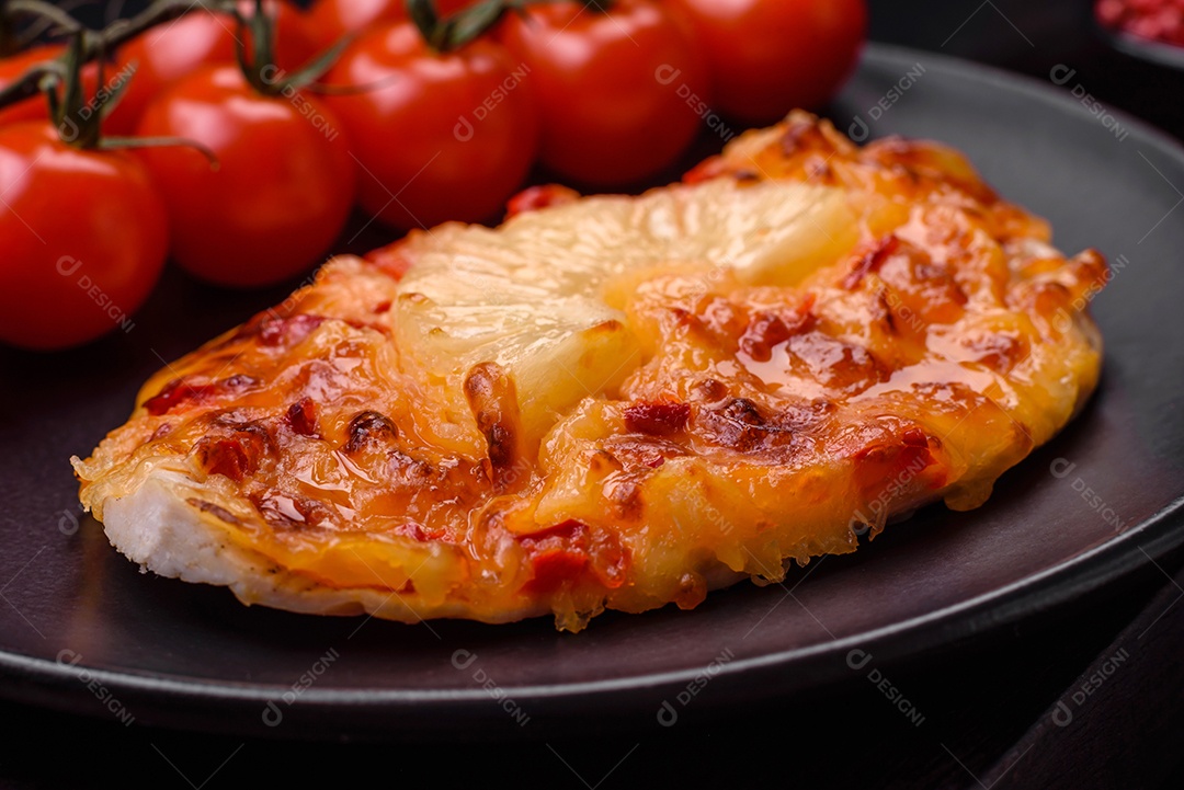 Filé de frango grelhado em forma de bife com tomate, abacaxi e queijo sobre fundo escuro de concreto