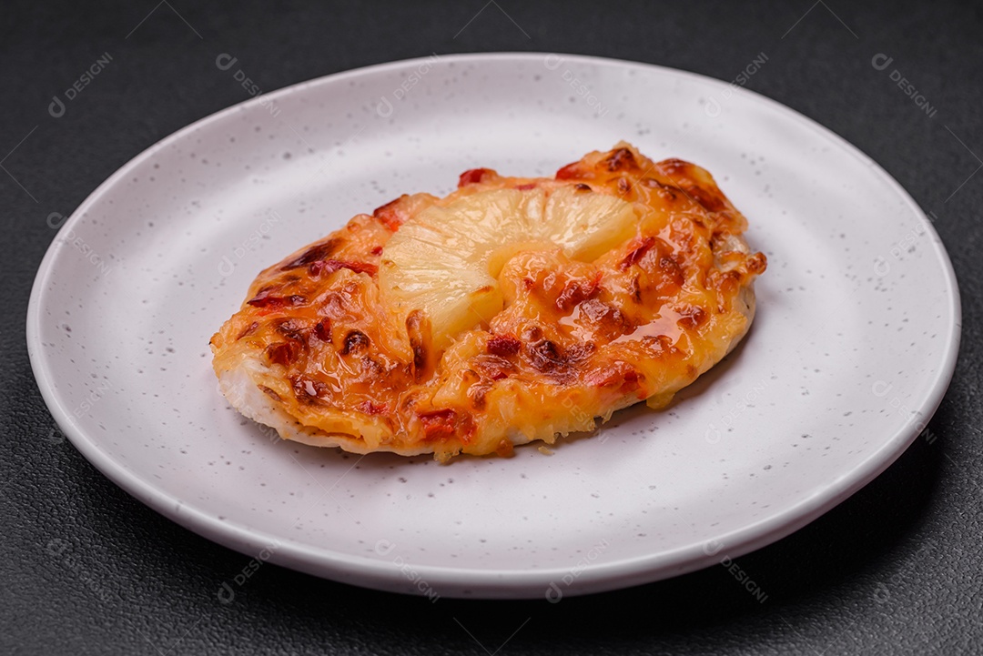 Filé de frango grelhado em forma de bife com tomate, abacaxi e queijo sobre fundo escuro de concreto