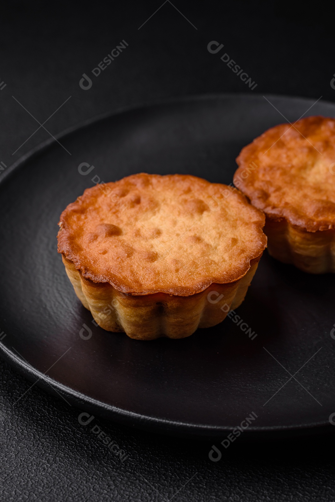 Delicioso bolinho assado ou tortinha com queijo e passas em um fundo escuro texturizado