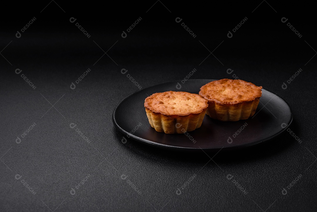 Delicioso bolinho assado ou tortinha com queijo e passas em um fundo escuro texturizado