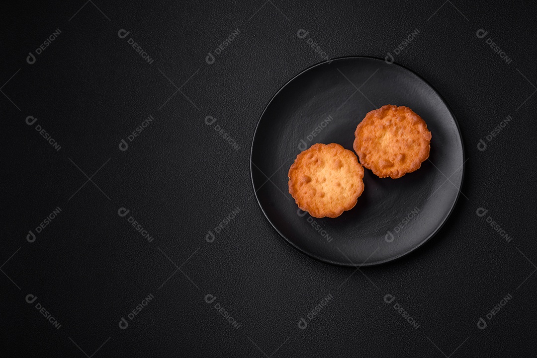 Delicioso bolinho assado ou tortinha com queijo e passas em um fundo escuro texturizado