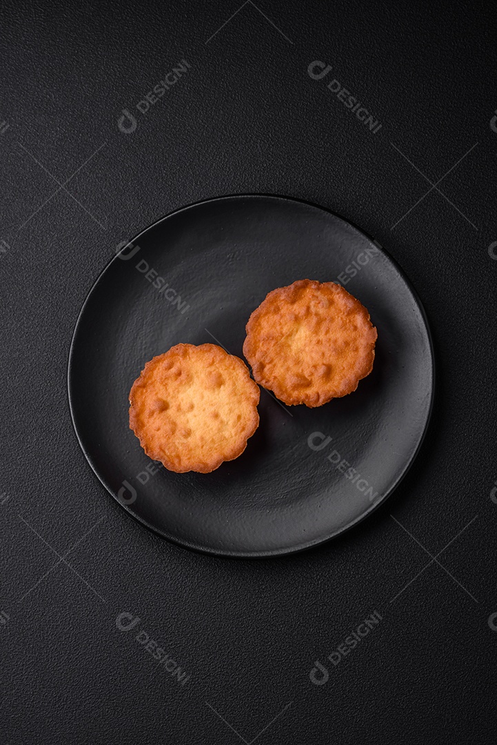 Delicioso bolinho assado ou tortinha com queijo e passas em um fundo escuro texturizado