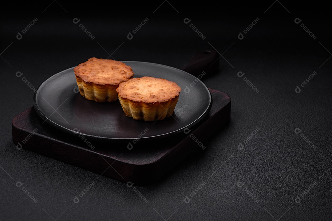 Delicioso bolinho assado ou tortinha com queijo e passas em um fundo escuro texturizado