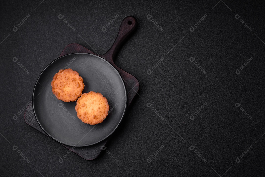 Delicioso bolinho assado ou tortinha com queijo e passas em um fundo escuro texturizado