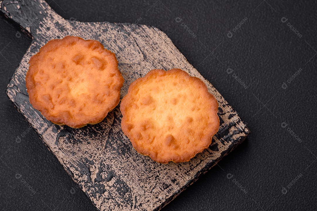 Delicioso bolinho assado ou tortinha com queijo e passas em um fundo escuro texturizado
