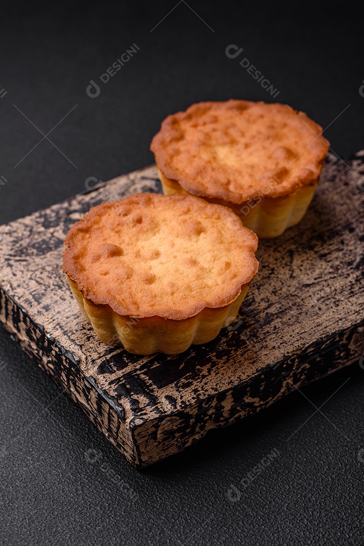 Delicioso bolinho assado ou tortinha com queijo e passas em um fundo escuro texturizado