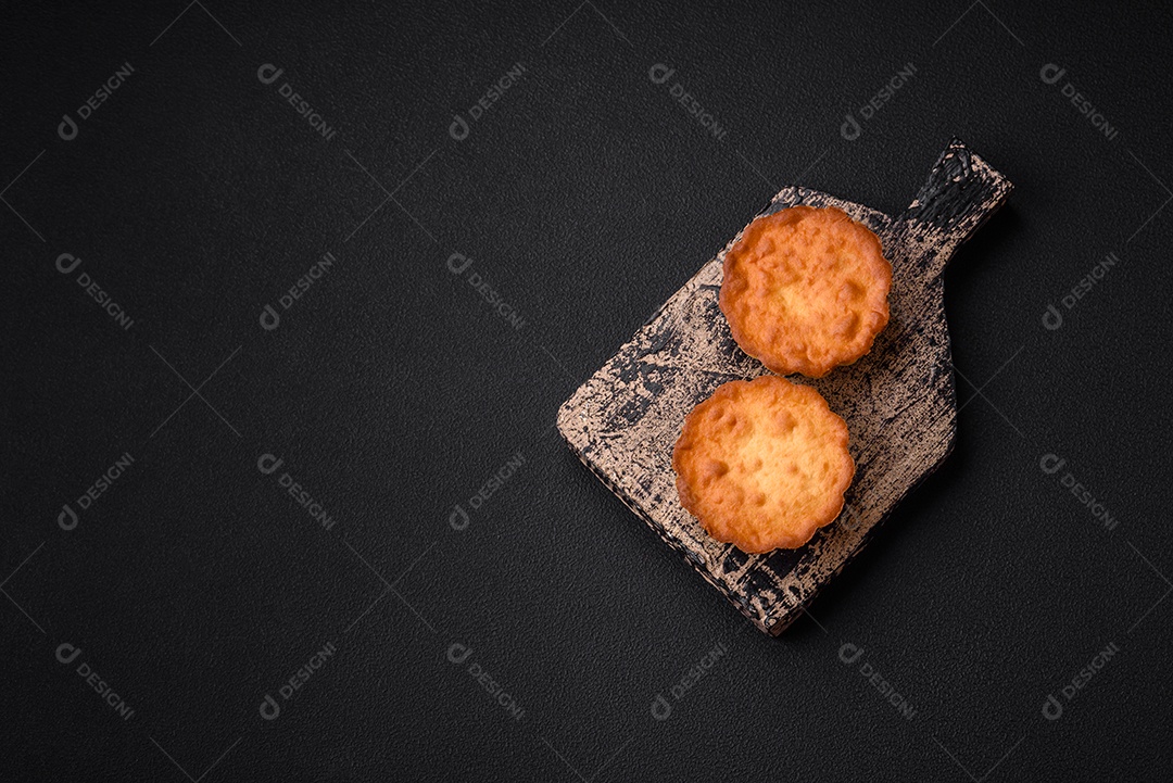 Delicioso bolinho assado ou tortinha com queijo e passas em um fundo escuro texturizado