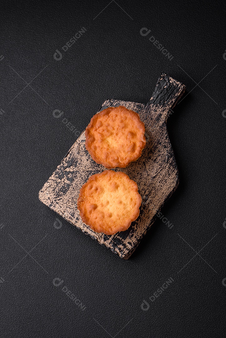 Delicioso bolinho assado ou tortinha com queijo e passas em um fundo escuro texturizado