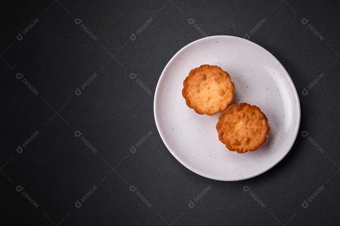 Delicioso bolinho assado ou tortinha com queijo e passas em um fundo escuro texturizado