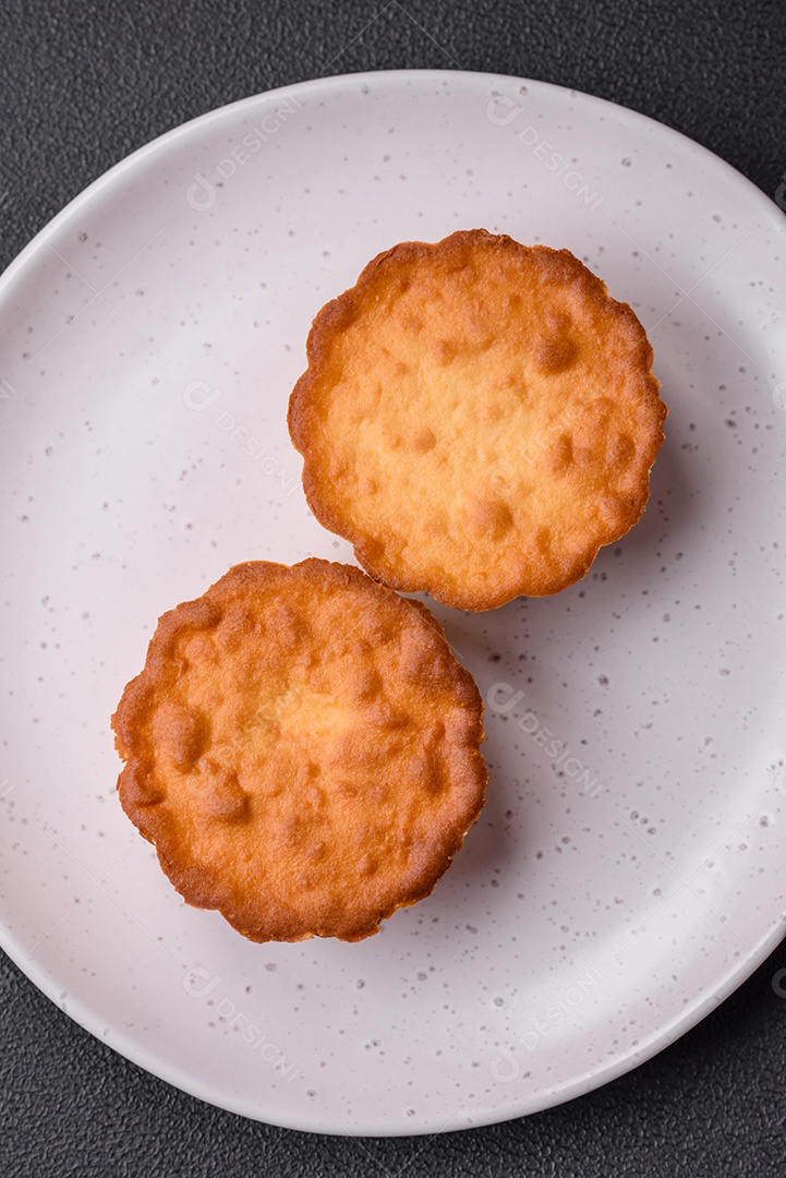 Delicioso bolinho assado ou tortinha com queijo e passas em um fundo escuro texturizado