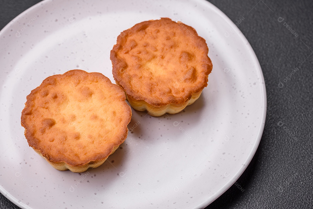 Delicioso bolinho assado ou tortinha com queijo e passas em um fundo escuro texturizado