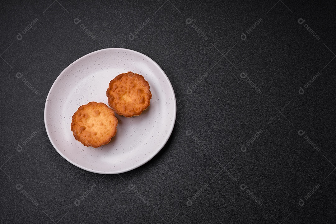 Delicioso bolinho assado ou tortinha com queijo e passas em um fundo escuro texturizado