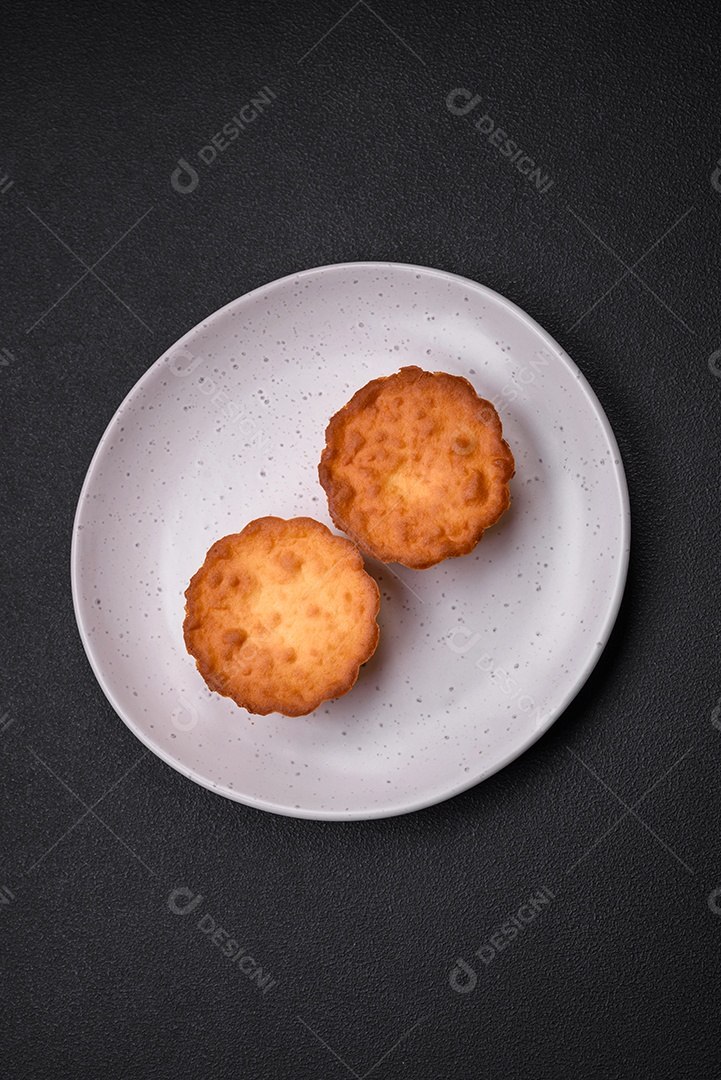 Delicioso bolinho assado ou tortinha com queijo e passas em um fundo escuro texturizado