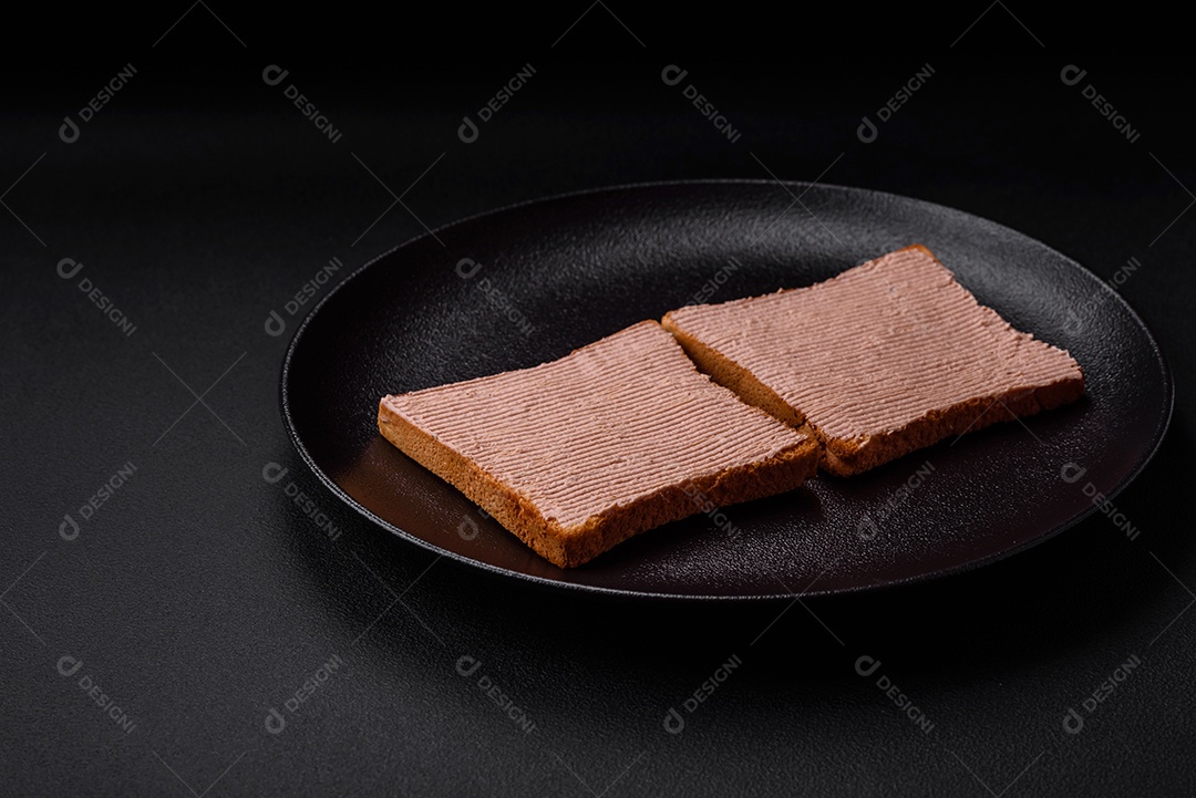 Deliciosa torrada crocante com frango ou patê de ganso com sal e especiarias sobre um fundo escuro de concreto