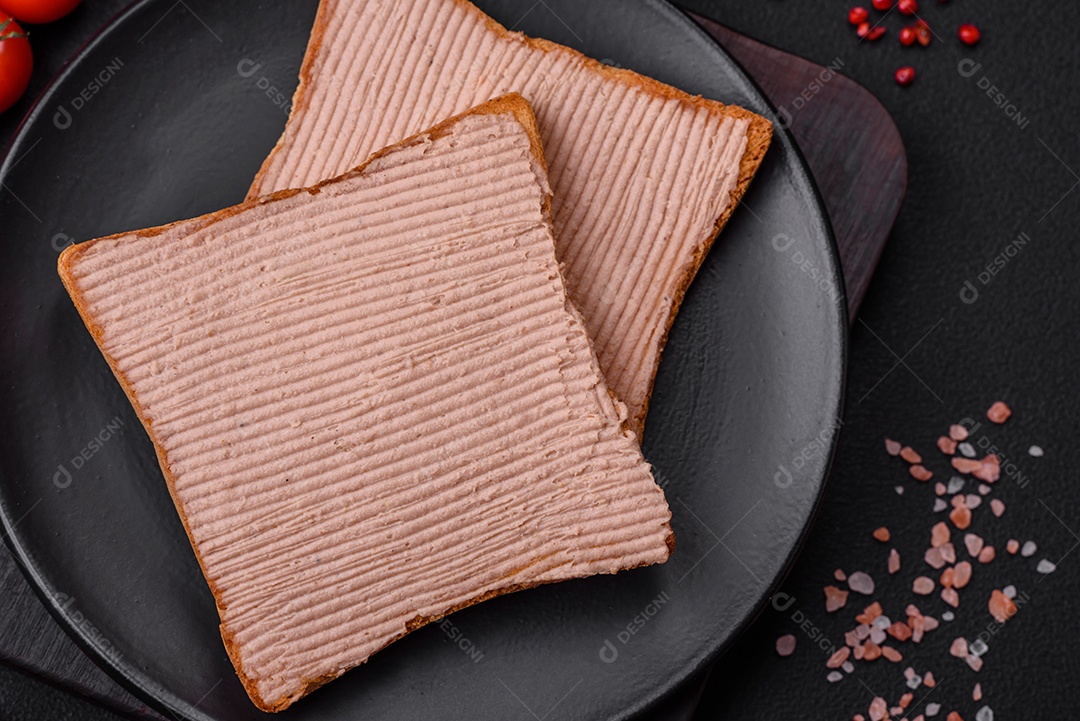 Deliciosa torrada crocante com frango ou patê de ganso com sal e especiarias sobre um fundo escuro de concreto