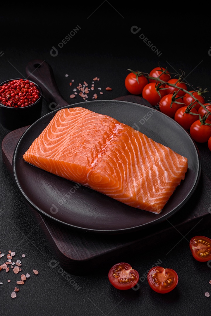 Filé de peixe vermelho salmão cru fresco com sal e especiarias sobre um fundo escuro de concreto