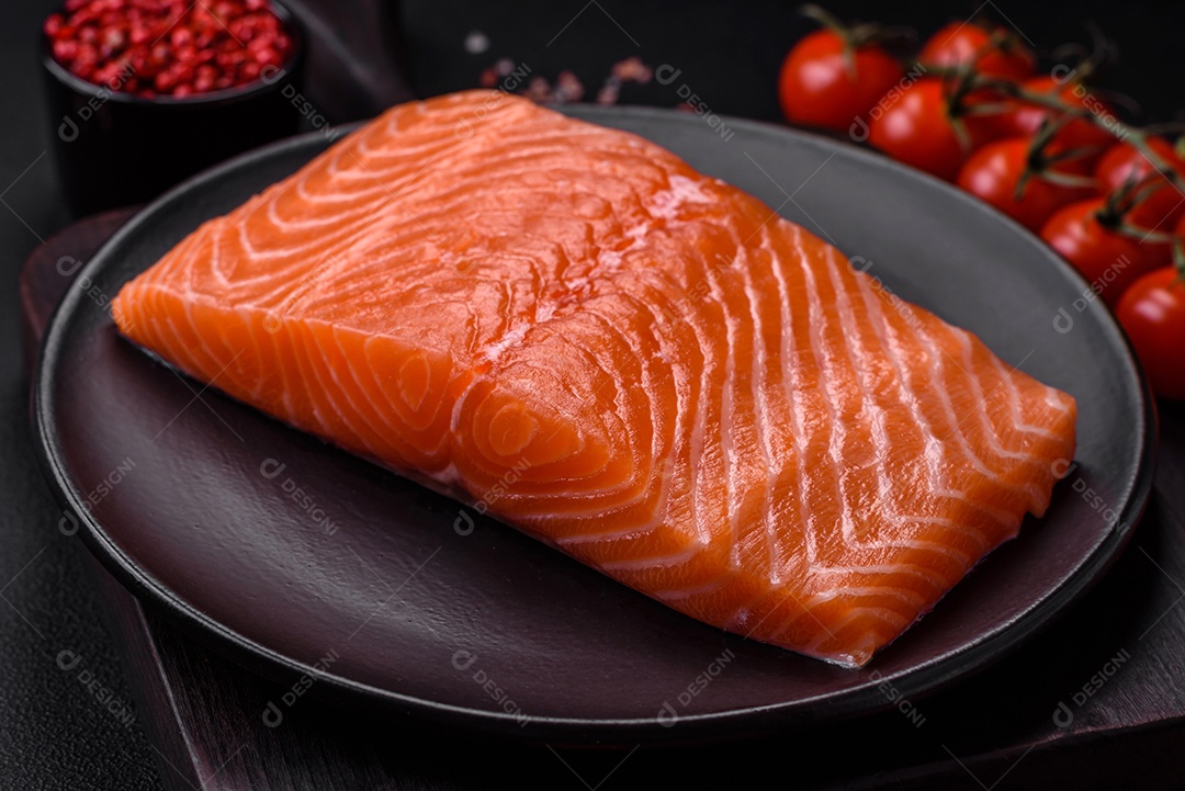 Filé de peixe vermelho salmão cru fresco com sal e especiarias sobre um fundo escuro de concreto