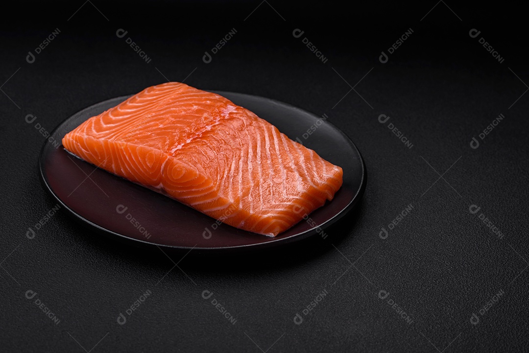 Filé de peixe vermelho salmão cru fresco com sal e especiarias sobre um fundo escuro de concreto