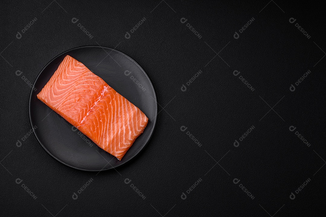 Filé de peixe vermelho salmão cru fresco com sal e especiarias sobre um fundo escuro de concreto