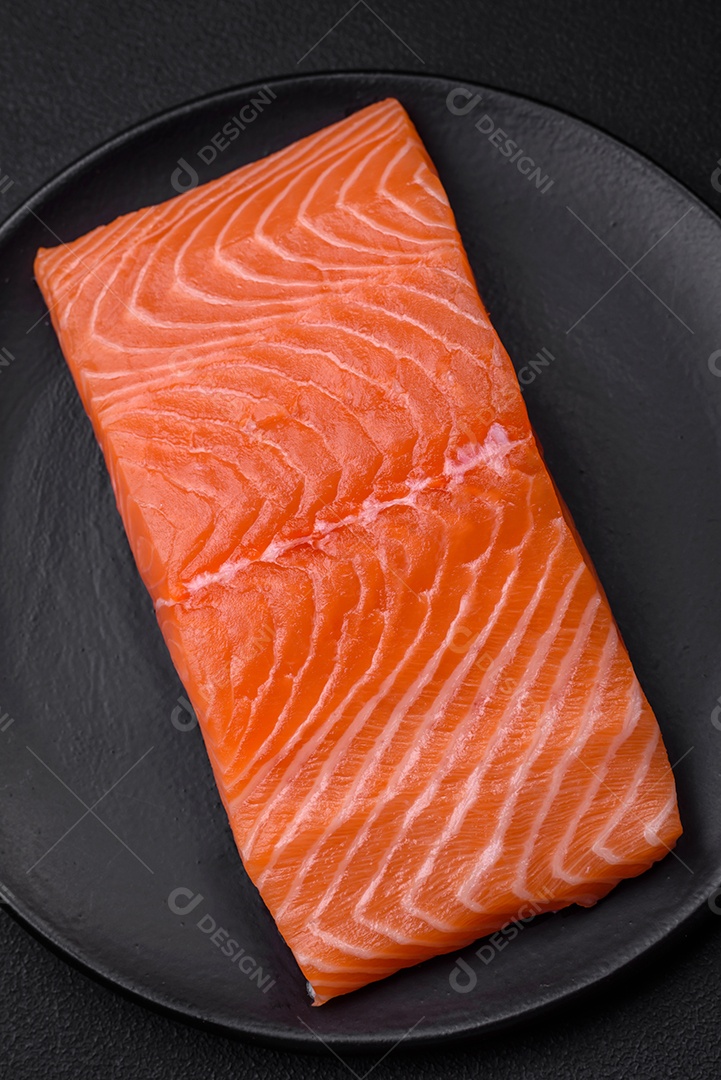 Filé de peixe vermelho salmão cru fresco com sal e especiarias sobre um fundo escuro de concreto