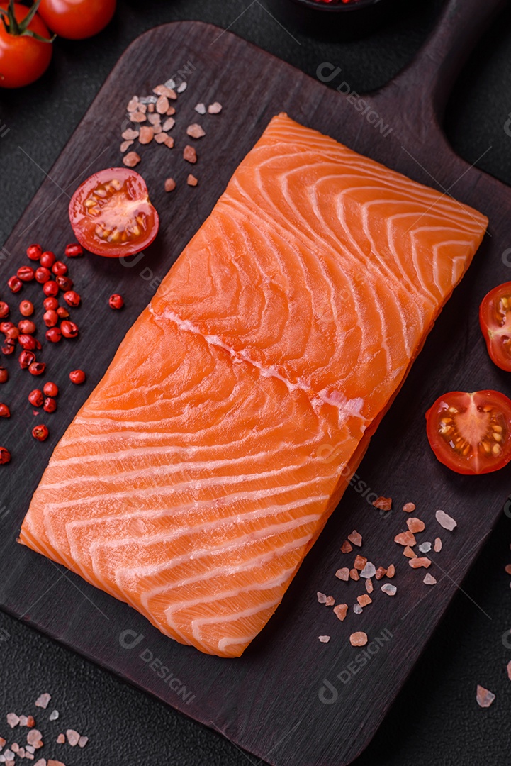 Filé de peixe vermelho salmão cru fresco com sal e especiarias sobre um fundo escuro de concreto