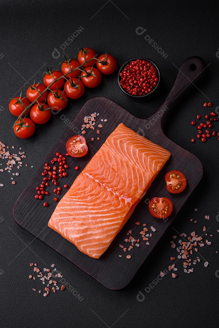 Filé de peixe vermelho salmão cru fresco com sal e especiarias sobre um fundo escuro de concreto