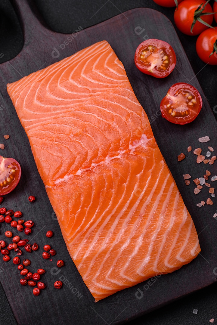 Filé de peixe vermelho salmão cru fresco com sal e especiarias sobre um fundo escuro de concreto