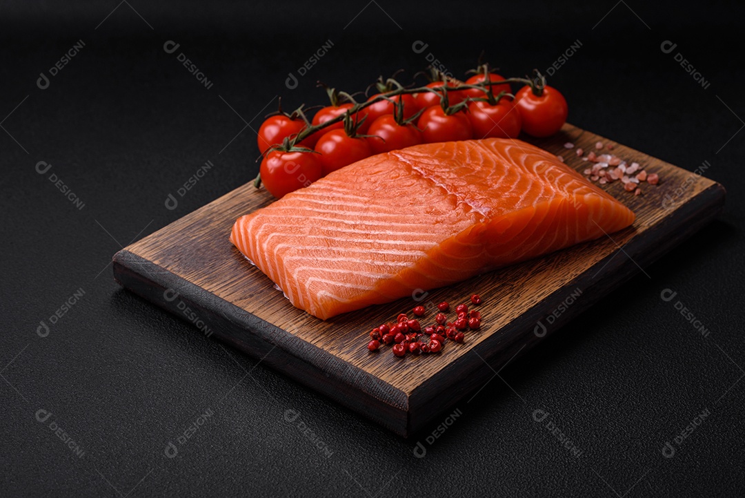 Filé de peixe vermelho salmão cru fresco com sal e especiarias sobre um fundo escuro de concreto