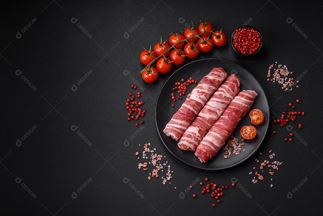 Carne picada crua embrulhada em bacon com sal e especiarias ou cevapcici sobre fundo escuro de concreto