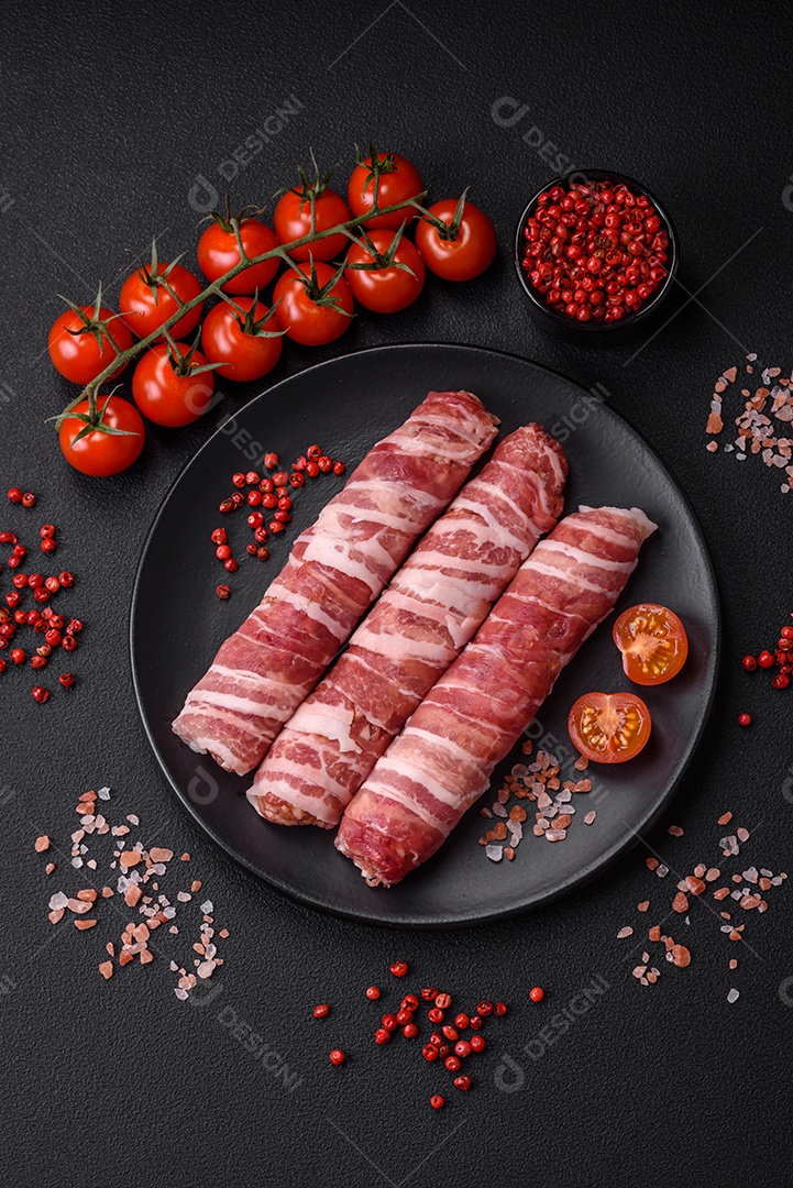 Carne picada crua embrulhada em bacon com sal e especiarias ou cevapcici sobre fundo escuro de concreto