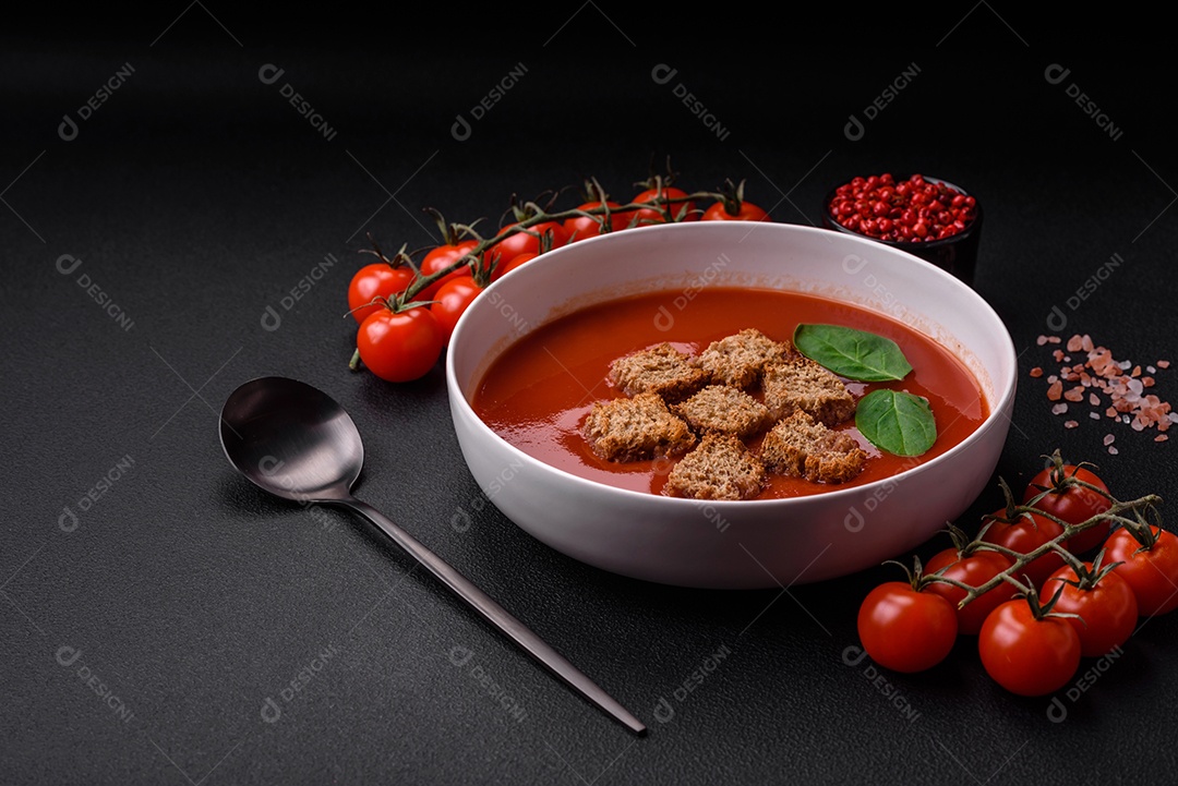Delicioso gaspacho fresco com pão ralado, sal e especiarias numa placa cerâmica sobre um fundo escuro de concreto
