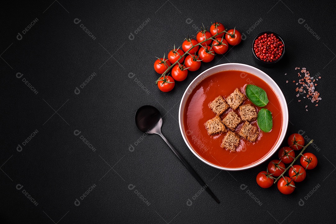Delicioso gaspacho fresco com pão ralado, sal e especiarias numa placa cerâmica sobre um fundo escuro de concreto