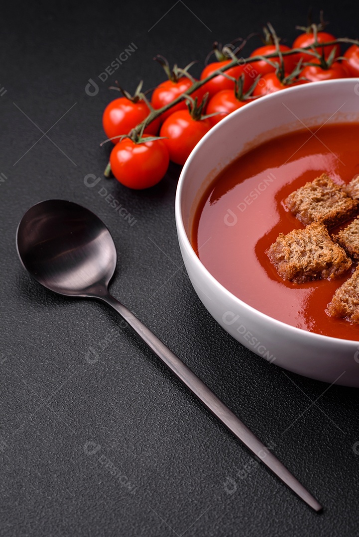 Delicioso gaspacho fresco com pão ralado, sal e especiarias numa placa cerâmica sobre um fundo escuro de concreto