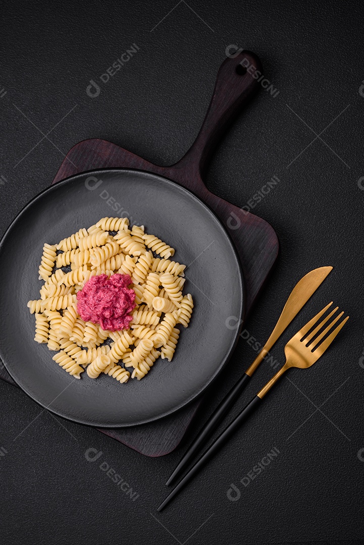 Deliciosa massa fusilli com pesto de beterraba, parmesão, sal e especiarias sobre um fundo escuro de concreto