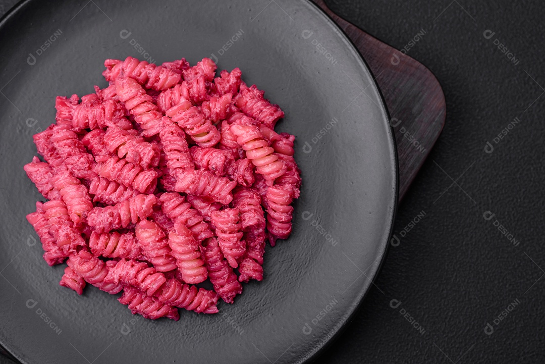 Deliciosa massa fusilli com pesto de beterraba, parmesão, sal e especiarias sobre um fundo escuro de concreto