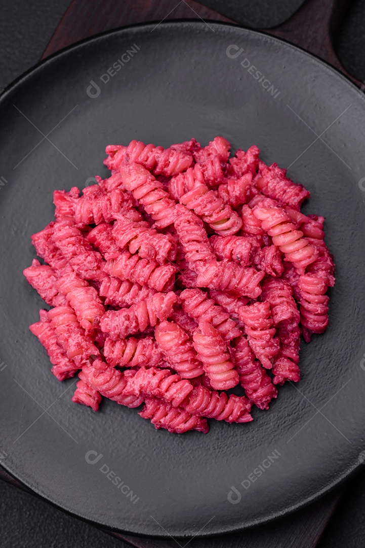 Deliciosa massa fusilli com pesto de beterraba, parmesão, sal e especiarias sobre um fundo escuro de concreto