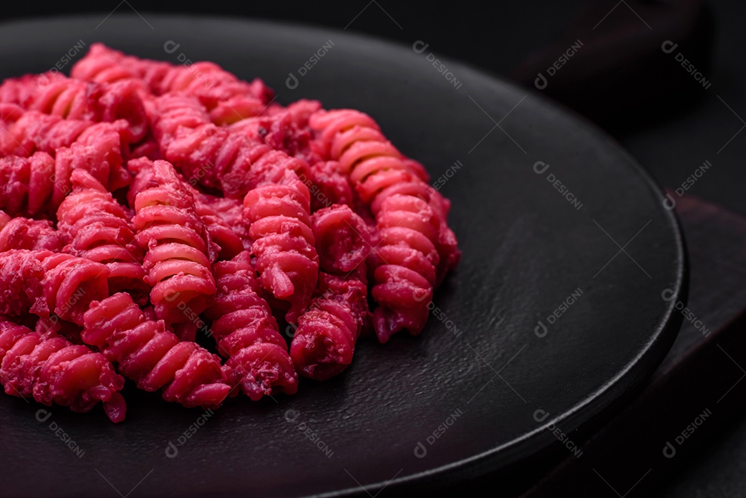 Deliciosa massa fusilli com pesto de beterraba, parmesão, sal e especiarias sobre um fundo escuro de concreto