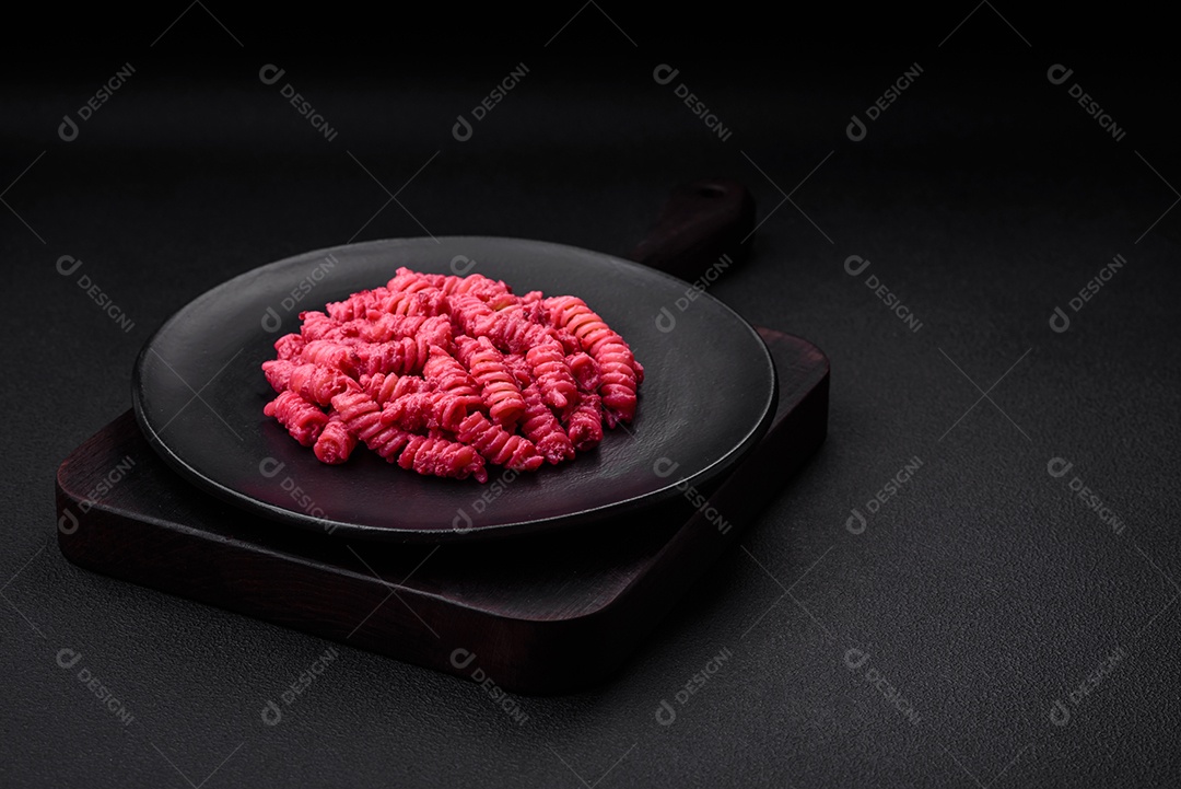 Deliciosa massa fusilli com pesto de beterraba, parmesão, sal e especiarias sobre um fundo escuro de concreto