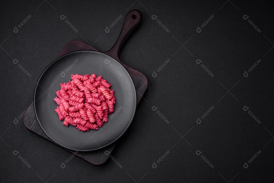 Deliciosa massa fusilli com pesto de beterraba, parmesão, sal e especiarias sobre um fundo escuro de concreto